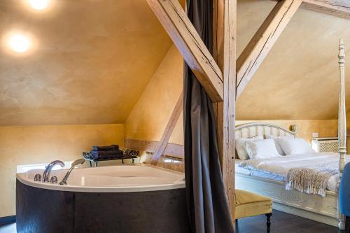 a bathroom with a tub next to a bed at Kurpiai - Suites & SPA in Klaipėda