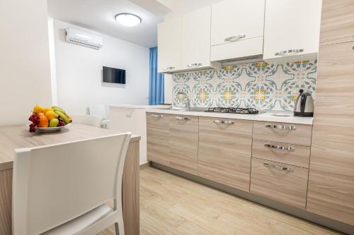 una cocina con armarios de madera y un bol de fruta en una barra en Agio Apartments Diamante - Bilocale, en Diamante