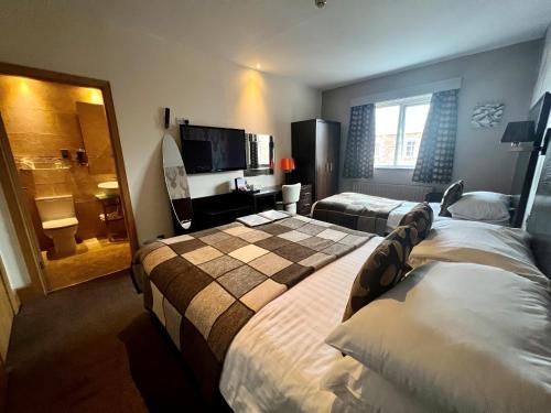 a hotel room with two beds and a bathroom at Inn On The Prom At The Fernlea Hotel in Lytham St Annes