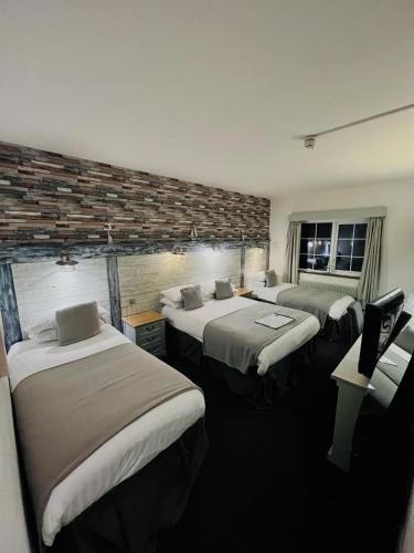 a room with three beds and a tv in it at Inn On The Prom At The Fernlea Hotel in Lytham St Annes
