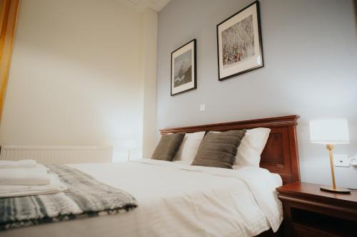 a bedroom with a white bed with a wooden headboard at 1909 Guesthouse in Kalavrita