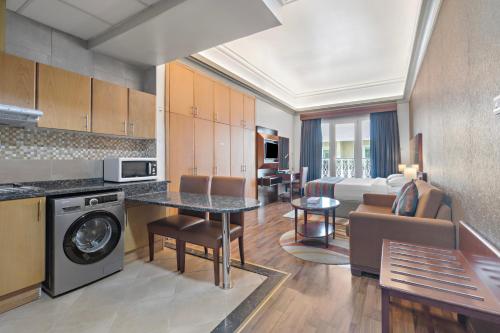 a kitchen with a living room and a living room with a dining room at Al Khoory Hotel Apartments Al Barsha in Dubai