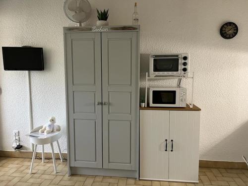 a kitchen with a cabinet with a microwave and a refrigerator at La Calypso in Cavalaire-sur-Mer