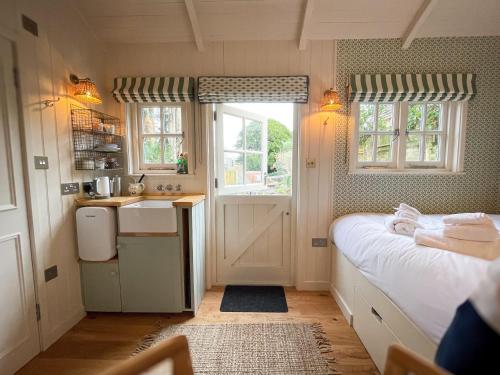 a small kitchen with a bed and a sink in a room at Shepherd's Hut at The Granary in Steyning