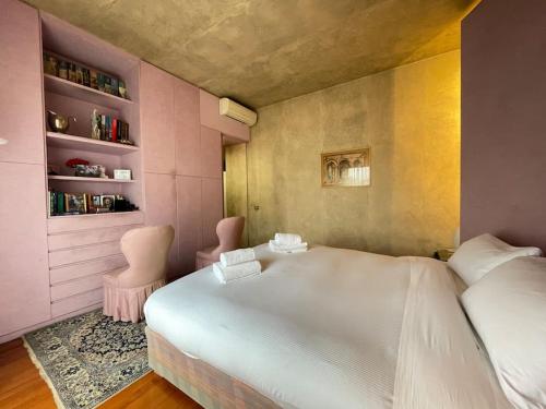 um quarto com uma cama branca e 2 cadeiras cor-de-rosa em Incantevole Villa con Giardino em Florença