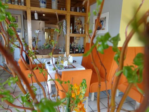 a restaurant with orange chairs and a table and some plants at Waldhotel Felschbachhof in Ulmet