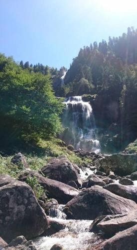 a waterfall on a mountain with rocks and trees at Le gîte du bonheur in Dalou