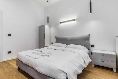 a white bedroom with a large bed and a nightstand at Viale Toscana, 2 PAX Wi-Fi in Milan