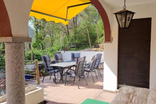 een patio met een tafel en stoelen en een parasol bij Haus Sonnenschein in Purasca