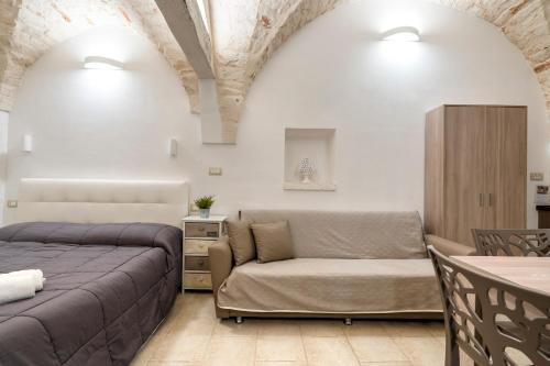a bedroom with a bed and a couch and a table at Casa Vita 49 in Ceglie Messapica