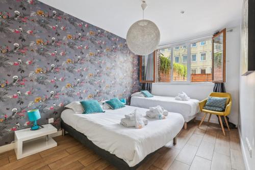 een slaapkamer met 2 bedden en een muur met bloemen bij 201 Suite Anne - Superbe appartement in Puteaux
