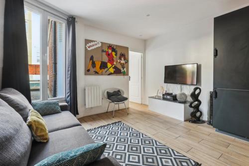 uma sala de estar com um sofá e uma televisão de ecrã plano em 201 Suite Anne - Superbe appartement em Puteaux