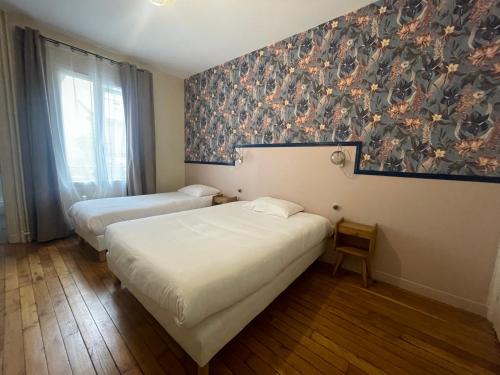 a room with two beds and a painting on the wall at Le Florus in Montrouge