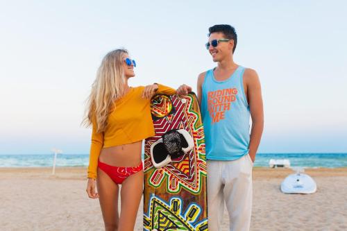 a man and a woman standing on the beach with a surfboard at Mangroovy Seafront condo - Great Kite Surfing in Hurghada