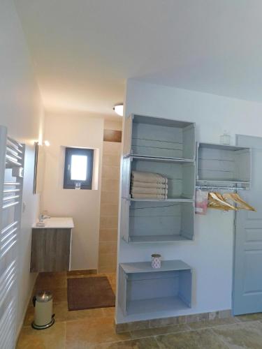 La salle de bains est pourvue d'étagères bleues et d'un lavabo. dans l'établissement LE HANGAR AVEC PISCINE EN DORDOGNE, à Veyrines-de-Domme