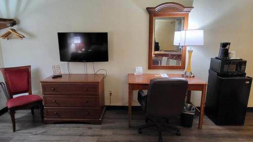 a hotel room with a desk and a television and a chair at Super 8 by Wyndham Canton/Livonia Area in Canton