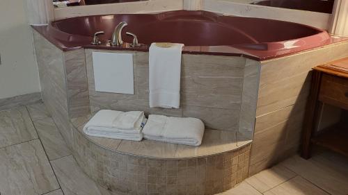 a bathroom with a tub with towels and a sink at Super 8 by Wyndham Canton/Livonia Area in Canton