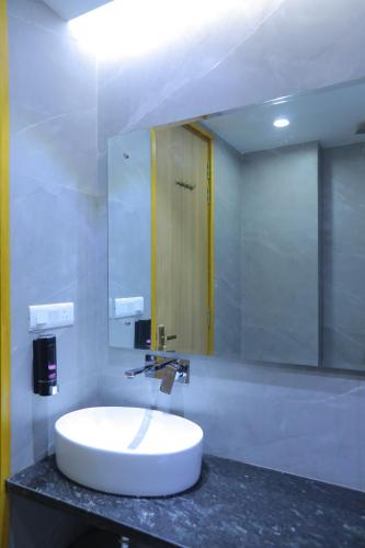 uma casa de banho com um lavatório branco e um espelho. em Hotel The Glitz em Nova Deli