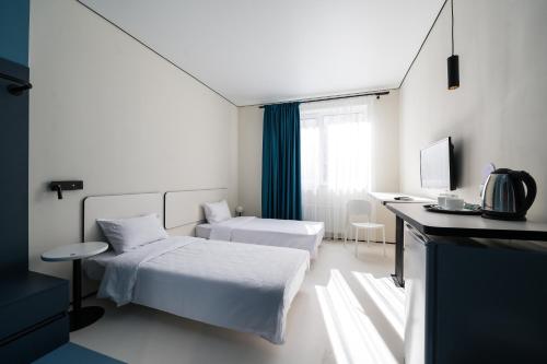 Habitación blanca con 2 camas y escritorio. en Ultramarinn Hotel, en Odessa