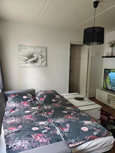 una camera da letto con un letto fiorito di Kaunis kaksio lähellä rautatieasemaa a Hämeenlinna