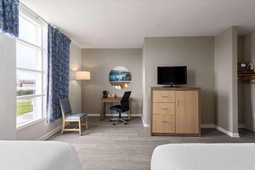 a room with a bedroom with a desk and a television at Days Inn by Wyndham Kill Devil Hills Oceanfront - Wilbur in Kill Devil Hills