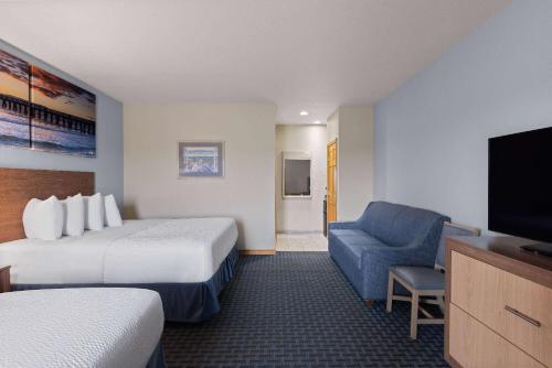 a hotel room with a bed and a couch and a television at Days Inn by Wyndham Kill Devil Hills Oceanfront - Wilbur in Kill Devil Hills