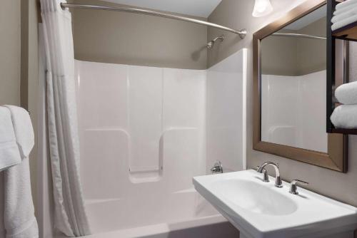 a white bathroom with a sink and a mirror at Days Inn by Wyndham Kill Devil Hills Oceanfront - Wilbur in Kill Devil Hills