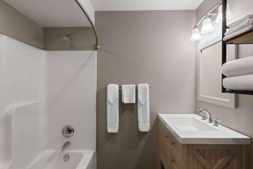 a white bathroom with a sink and a bath tub at Days Inn by Wyndham Kill Devil Hills Oceanfront - Wilbur in Kill Devil Hills