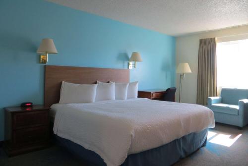 a hotel room with a large bed and a chair at Days Inn by Wyndham Alamosa in Alamosa