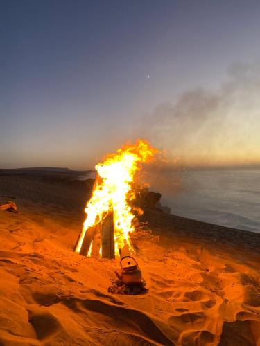 a fire on a beach with the ocean in the background at Surf Break Morocco in Imsouane