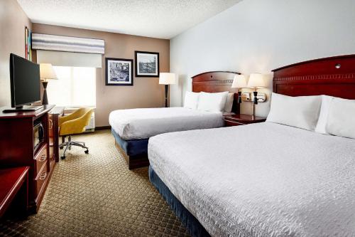 a hotel room with two beds and a flat screen tv at Hampton Inn Longmont in Longmont