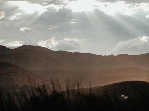a view of a mountain with a car in the distance at Landrani Farmstay in Oudtshoorn