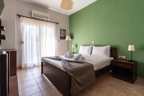 a bedroom with a large bed with a green wall at Hara Studios in Plataria