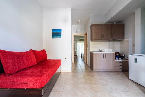 a living room with a red couch and a kitchen at Hara Studios in Plataria