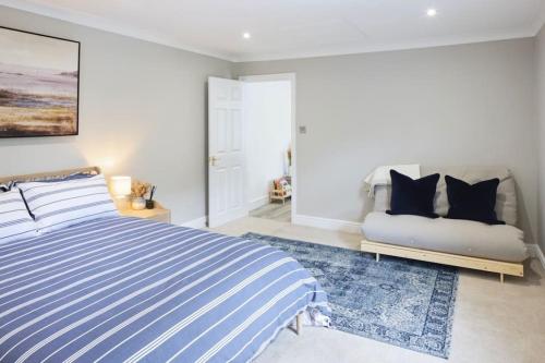 a bedroom with a blue and white striped bed and a couch at The Dolman at Ferndown Forest Golf Course in Ferndown