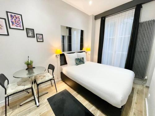 a bedroom with a large white bed and a table at Charming Studette Paris La Défense in Puteaux