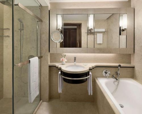 a bathroom with a sink and a tub and a mirror at Shangri-La Kuala Lumpur in Kuala Lumpur