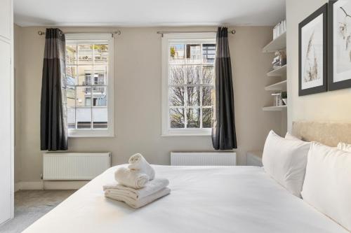 um quarto com uma cama branca e 2 janelas em Heavenly Stays - Victoria em Londres