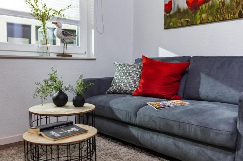 ein Wohnzimmer mit einem blauen Sofa und 2 Tischen in der Unterkunft Wohnung Ostbake in Borkum
