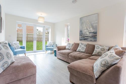 a living room with a couch and chairs and windows at Pine Trees - 4 bed home in The Witterings in Chichester