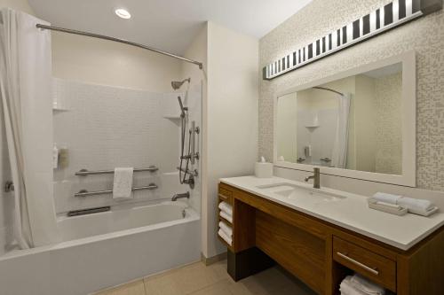 a bathroom with a sink and a tub and a mirror at Home2 Suites By Hilton Baytown in Baytown