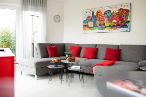a living room with a gray couch and red pillows at Haus Stranddüne in Borkum
