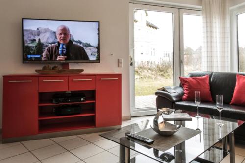 una sala de estar con un centro de entretenimiento rojo con TV de pantalla plana en Haus Stranddüne en Borkum
