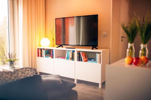 - un salon avec une télévision sur un centre de divertissement blanc dans l'établissement Haus Jelena Appartement 5, à Borkum