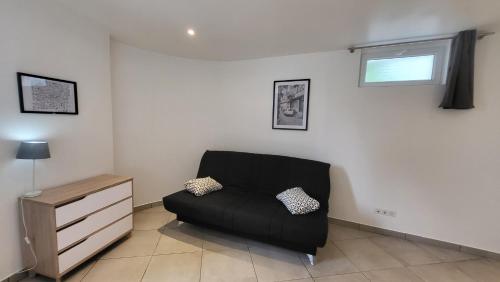 un canapé noir dans un salon avec une fenêtre dans l'établissement studio Les merles à Saint-Égrève, à Saint-Égrève