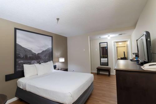 a bedroom with a bed and a desk with a television at Super 8 by Wyndham Prince George in Prince George