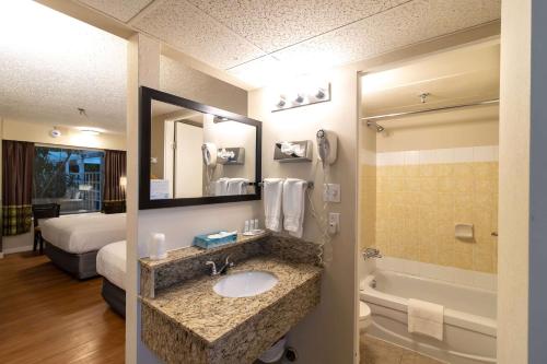 Super 8 by Wyndham Prince George في برينس جورج: غرفة في الفندق مع حمام مع حوض وحوض استحمام