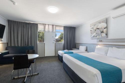 a hotel room with two beds and a desk at Comfort Inn Glenelg in Adelaide