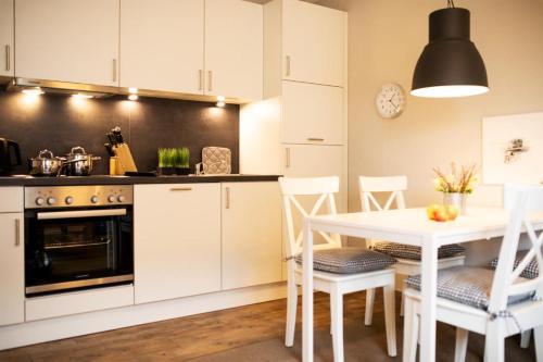 una cocina con armarios blancos y una mesa y sillas blancas. en Haus Jelena Appartement 2 en Borkum
