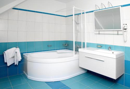 La salle de bains bleue et blanche est pourvue d'une baignoire et d'un lavabo. dans l'établissement Pivovar a restaurace Faltus, à Česká Třebová